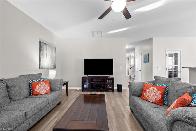 living area featuring visible vents, baseboards, a ceiling fan, stairway, and light wood finished floors