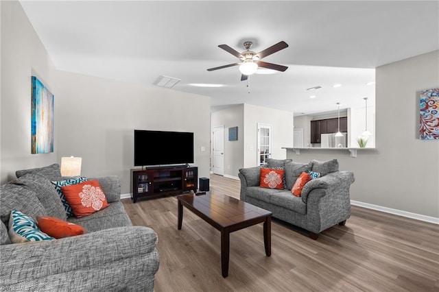 living area with light wood-style floors, visible vents, and baseboards