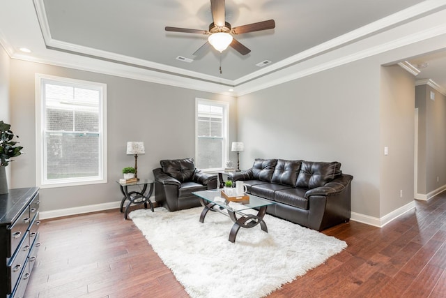 living room with plenty of natural light, dark hardwood / wood-style flooring, ceiling fan, and a tray ceiling