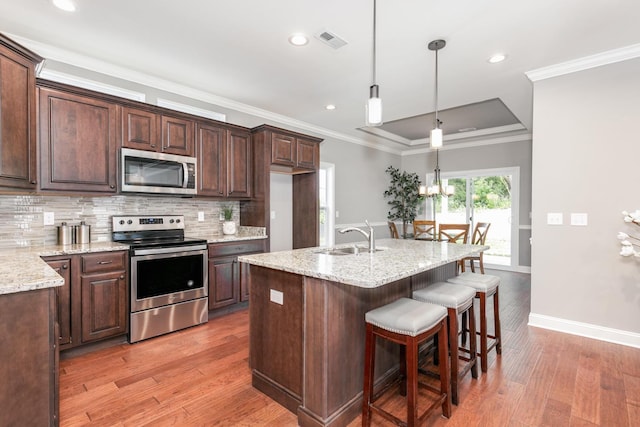 kitchen featuring pendant lighting, tasteful backsplash, stainless steel appliances, sink, and light hardwood / wood-style flooring