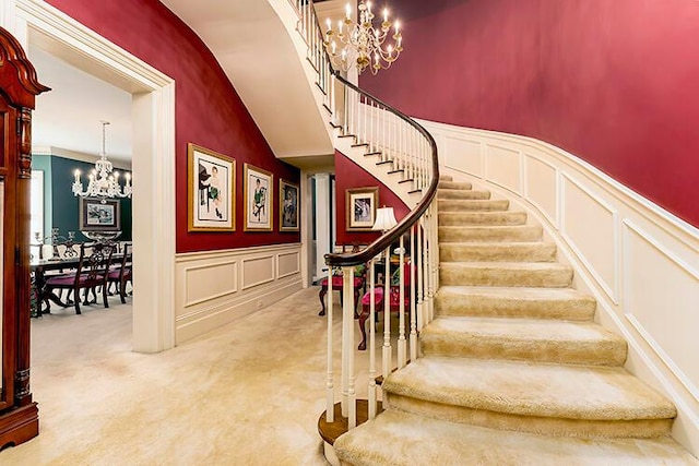 staircase featuring light colored carpet, a notable chandelier, and a towering ceiling