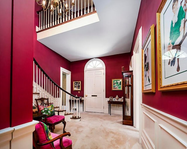 foyer entrance with an inviting chandelier and light carpet