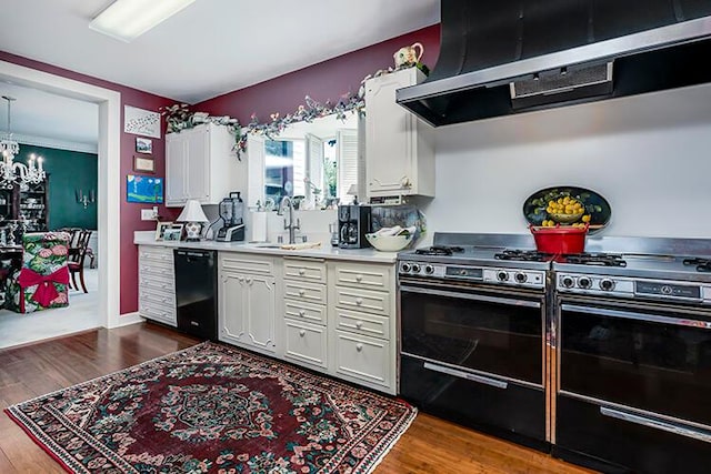 kitchen featuring an inviting chandelier, white cabinetry, dishwasher, and wall chimney range hood