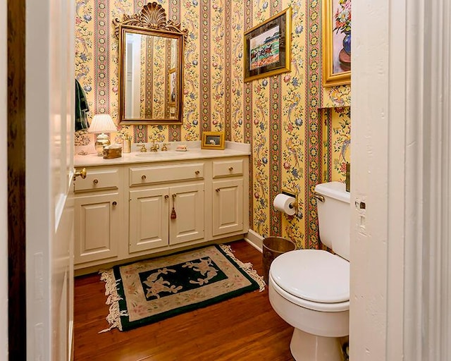 bathroom with toilet, hardwood / wood-style floors, and vanity