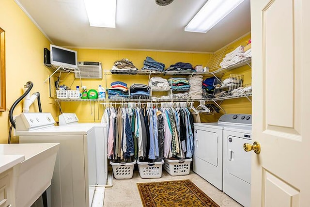 laundry room with a wall unit AC, separate washer and dryer, and sink