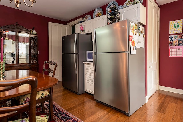 kitchen with stainless steel refrigerator, light wood-type flooring, and white cabinetry