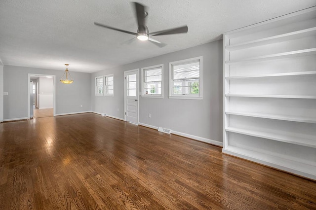 spare room featuring a healthy amount of sunlight, ceiling fan, a textured ceiling, and dark hardwood / wood-style flooring