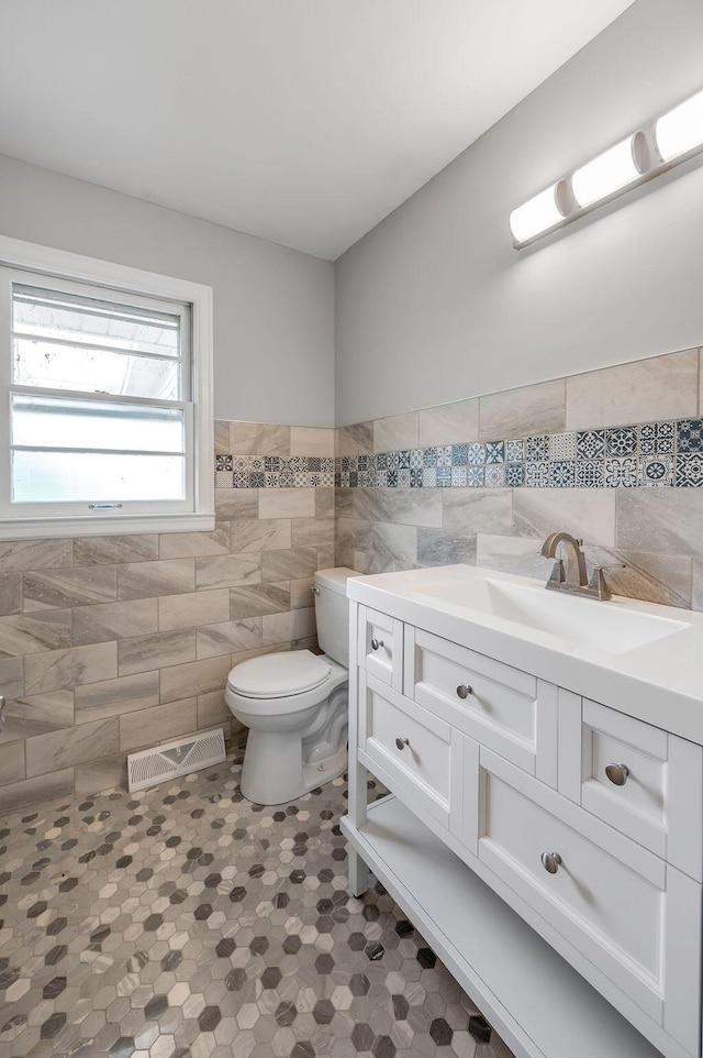 bathroom with tile walls, tile flooring, toilet, and vanity