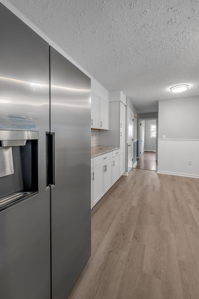 kitchen featuring high end refrigerator, light hardwood / wood-style floors, ornamental molding, and white cabinetry