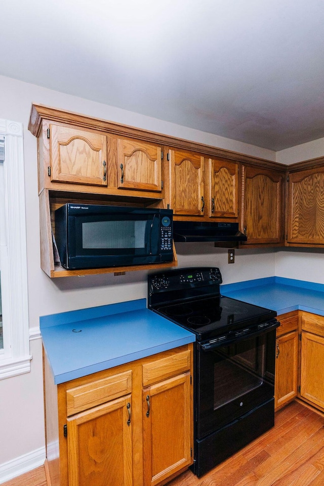 kitchen with light hardwood / wood-style floors and black appliances