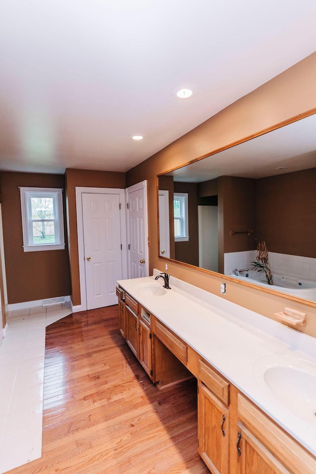 bathroom featuring a bath, dual vanity, and hardwood / wood-style flooring