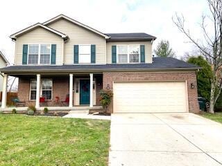 view of front of home with covered porch, a garage, and a front lawn