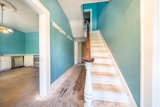 stairs featuring a chandelier, light hardwood / wood-style floors, and sink