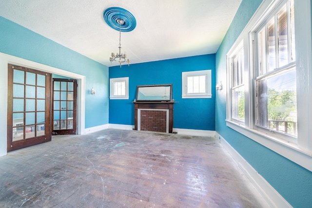 unfurnished living room featuring a notable chandelier and a textured ceiling