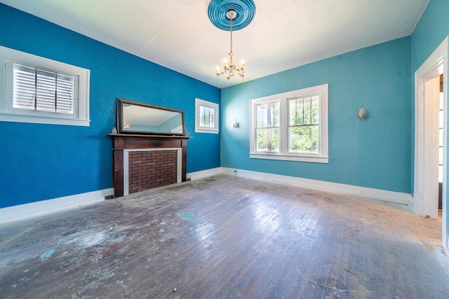 unfurnished living room featuring hardwood / wood-style floors, a textured ceiling, and a chandelier