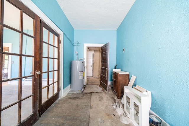 misc room featuring french doors, a textured ceiling, and electric water heater