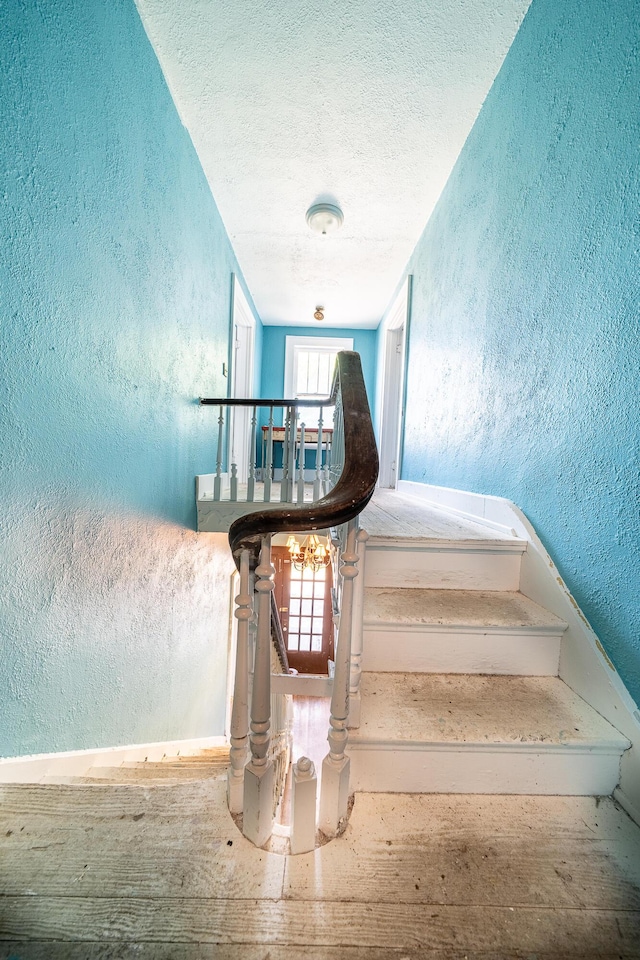 stairs with plenty of natural light and a textured ceiling