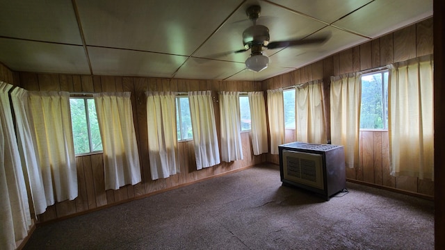 spare room featuring ceiling fan, dark carpet, and a wealth of natural light