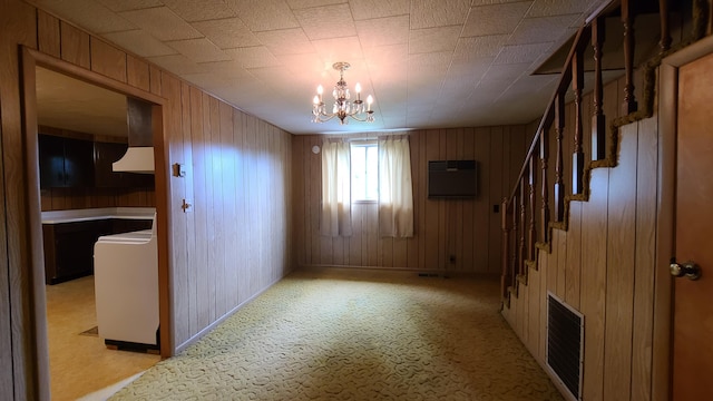 unfurnished room with wooden walls, light colored carpet, and a chandelier