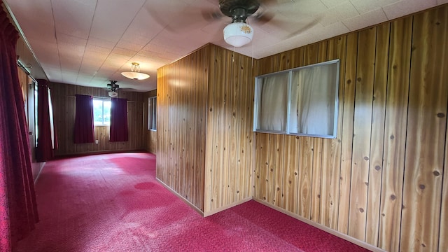 spare room with ceiling fan, light colored carpet, and wood walls