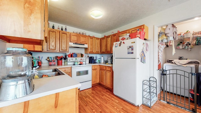 kitchen featuring white appliances, a textured ceiling, sink, and light wood-type flooring