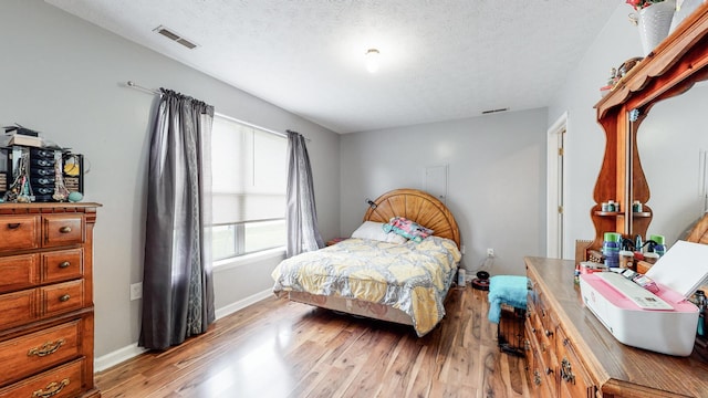 bedroom with a textured ceiling and light hardwood / wood-style floors