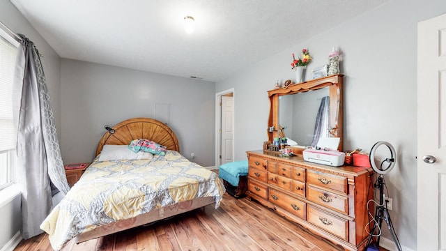 bedroom with light hardwood / wood-style floors and multiple windows