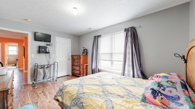 bedroom with a textured ceiling and light hardwood / wood-style flooring