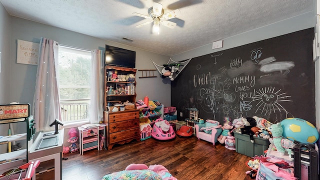 game room featuring a healthy amount of sunlight, ceiling fan, dark wood-type flooring, and a textured ceiling