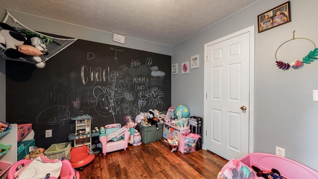 playroom with dark hardwood / wood-style flooring and a textured ceiling