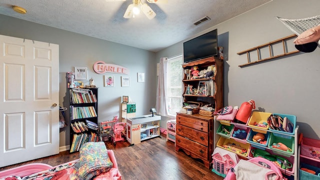 rec room with a textured ceiling, ceiling fan, and dark wood-type flooring