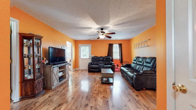 living room with ceiling fan, light hardwood / wood-style flooring, and a textured ceiling