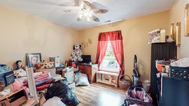 bedroom with a textured ceiling, light hardwood / wood-style floors, and ceiling fan