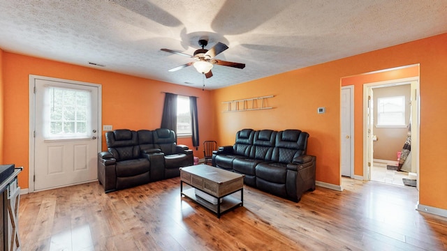 living room featuring ceiling fan, a textured ceiling, and light tile floors