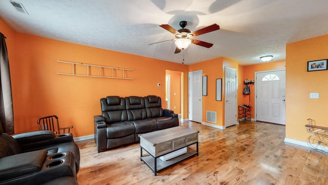 living room with ceiling fan, a textured ceiling, and light hardwood / wood-style flooring