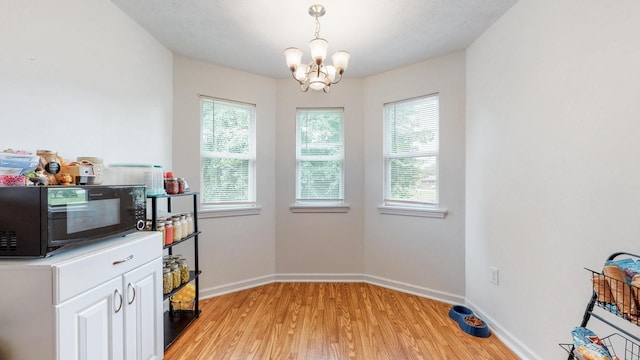 kitchen featuring white cabinetry, a chandelier, light hardwood / wood-style floors, and a healthy amount of sunlight