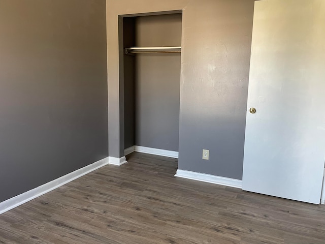 unfurnished bedroom featuring dark hardwood / wood-style floors and a closet