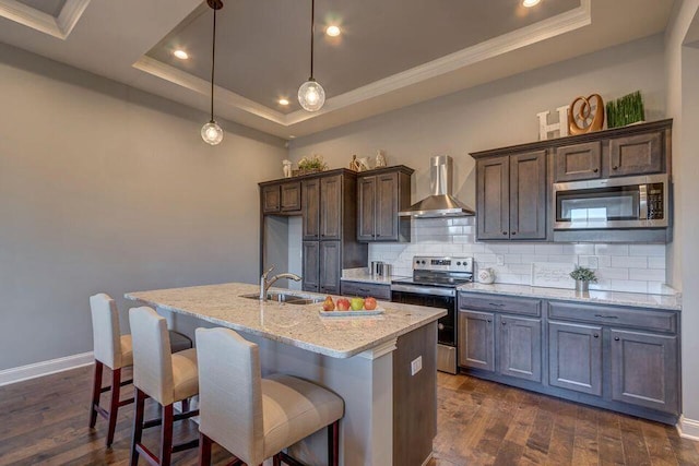 kitchen with dark hardwood / wood-style flooring, stainless steel appliances, backsplash, wall chimney range hood, and a raised ceiling