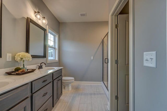 bathroom with a shower with shower door, toilet, tile floors, and dual bowl vanity