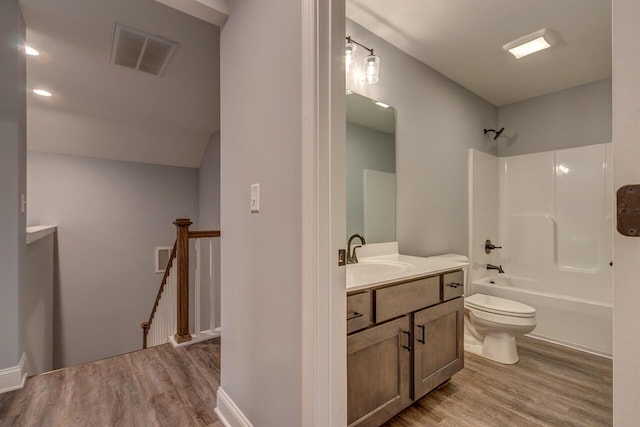 bathroom with visible vents, toilet, wood finished floors, vanity, and  shower combination