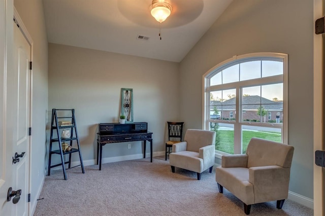 living area featuring ceiling fan, vaulted ceiling, and light colored carpet