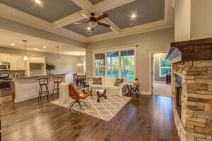 living room featuring coffered ceiling, dark hardwood / wood-style flooring, ceiling fan, and a fireplace