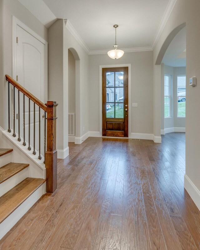 foyer entrance with ornamental molding, plenty of natural light, and light hardwood / wood-style floors