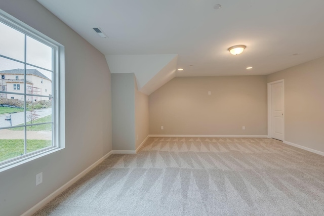 additional living space with light carpet and vaulted ceiling