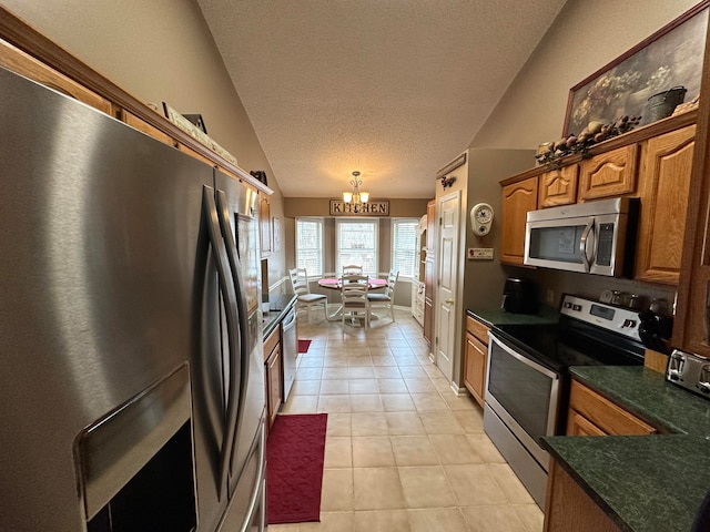 kitchen featuring a chandelier, a textured ceiling, stainless steel appliances, lofted ceiling, and light tile patterned floors