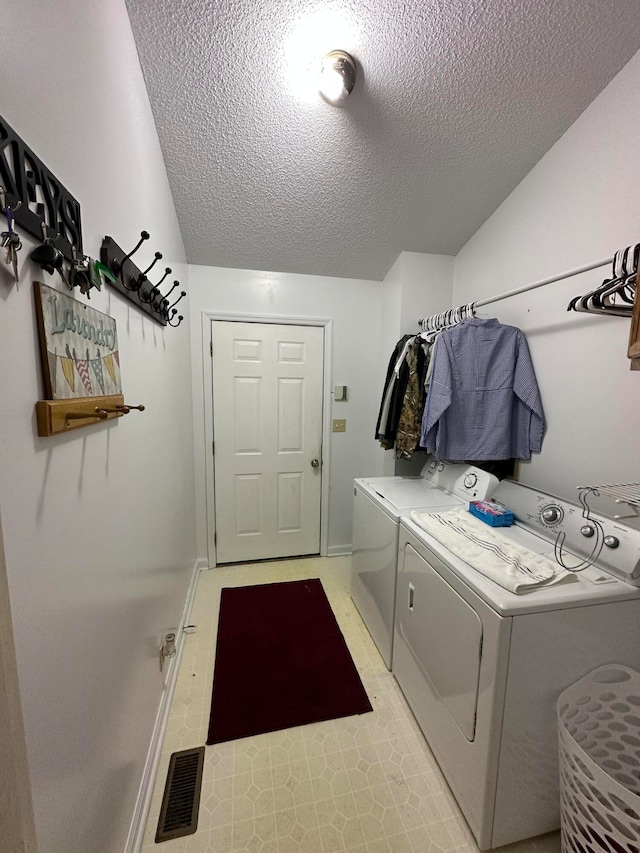 clothes washing area with a textured ceiling, light tile patterned floors, and independent washer and dryer