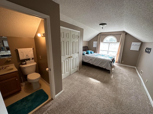 carpeted bedroom featuring lofted ceiling, a closet, sink, and a textured ceiling