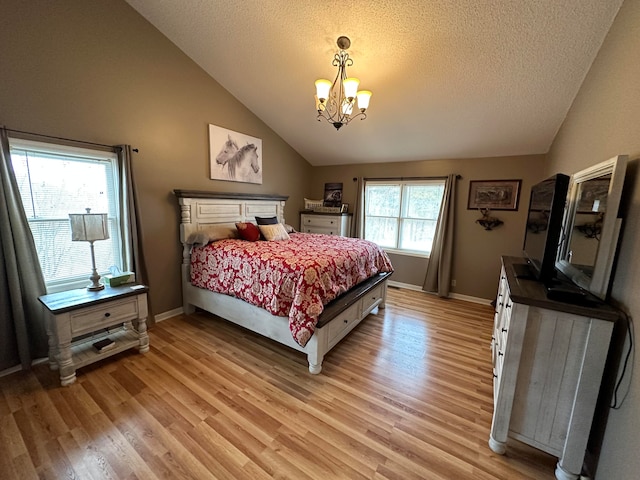 bedroom featuring light hardwood / wood-style flooring, an inviting chandelier, a textured ceiling, and high vaulted ceiling