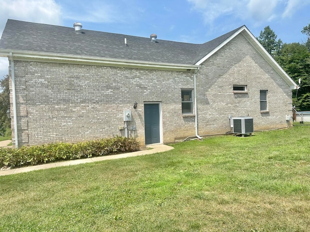 back of house with central air condition unit and a yard