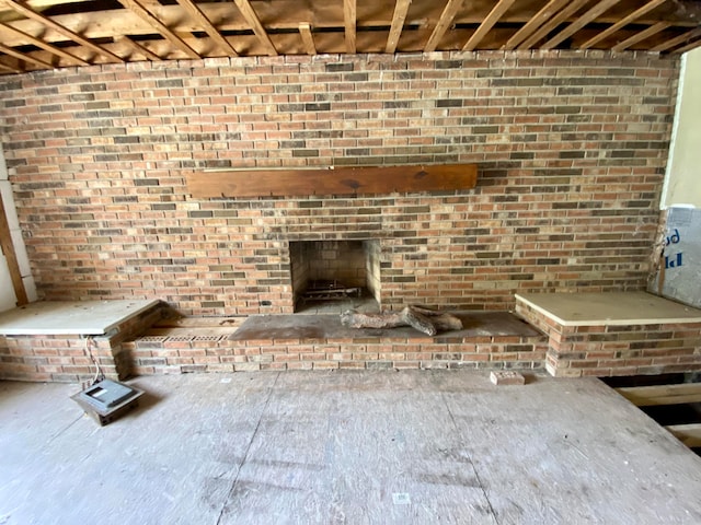 unfurnished living room featuring a fireplace and brick wall